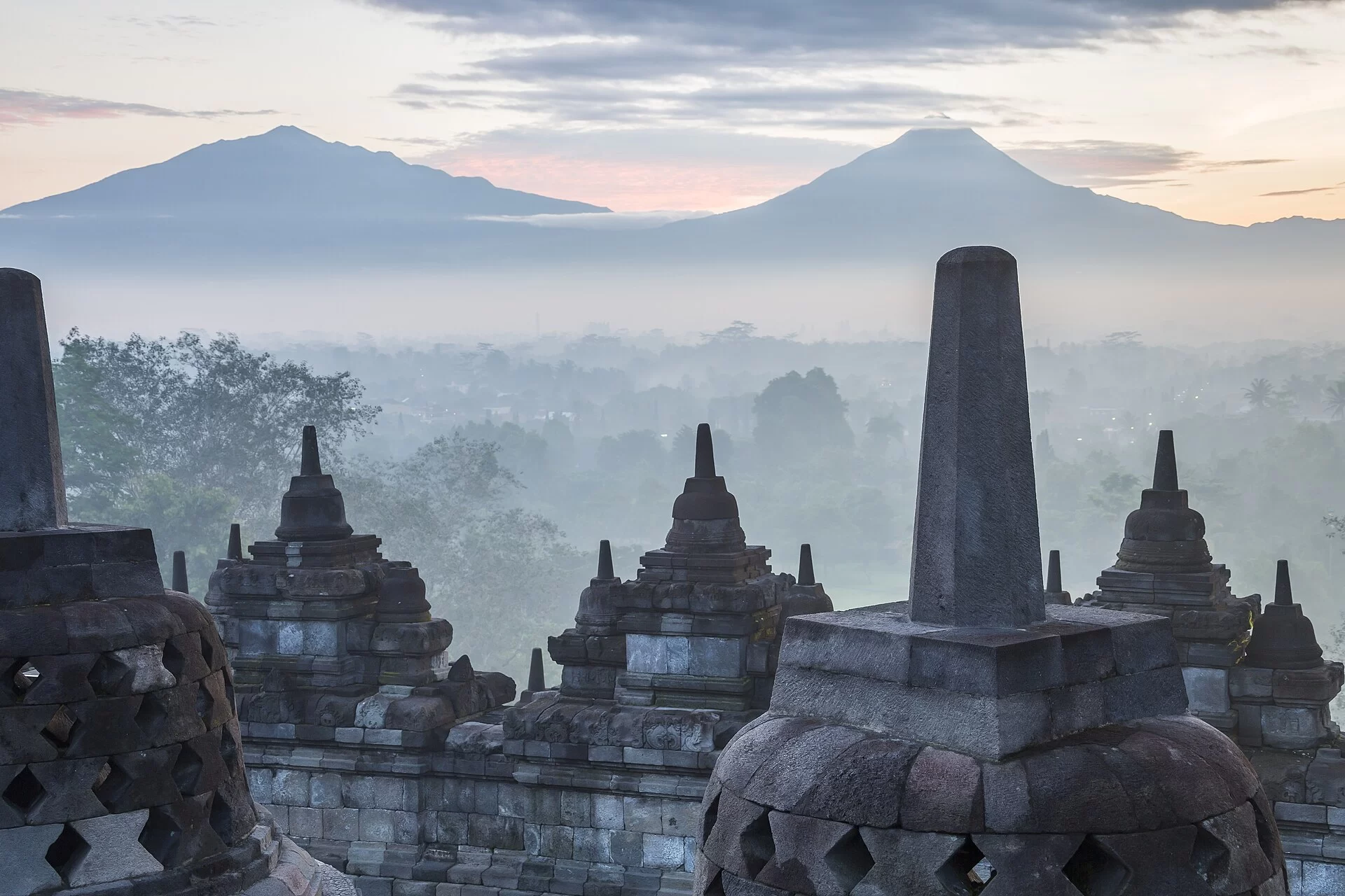 Les stupas de Borobudur dans la brume avec les volcans en arrière-plan, à Java, en Indonésie