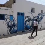 Une ruelle blanche ornée d'une fresque bleue à Djerbahood, sur l'île de Djerba
