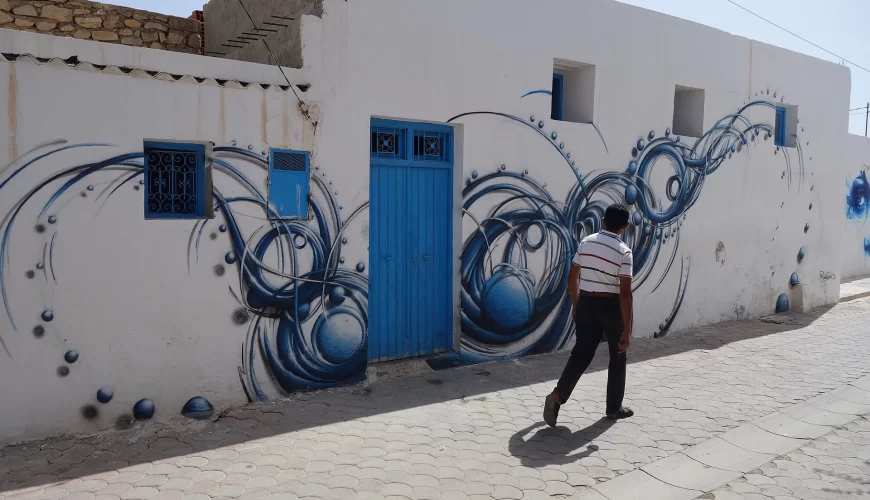 Une ruelle blanche ornée d'une fresque bleue à Djerbahood, sur l'île de Djerba