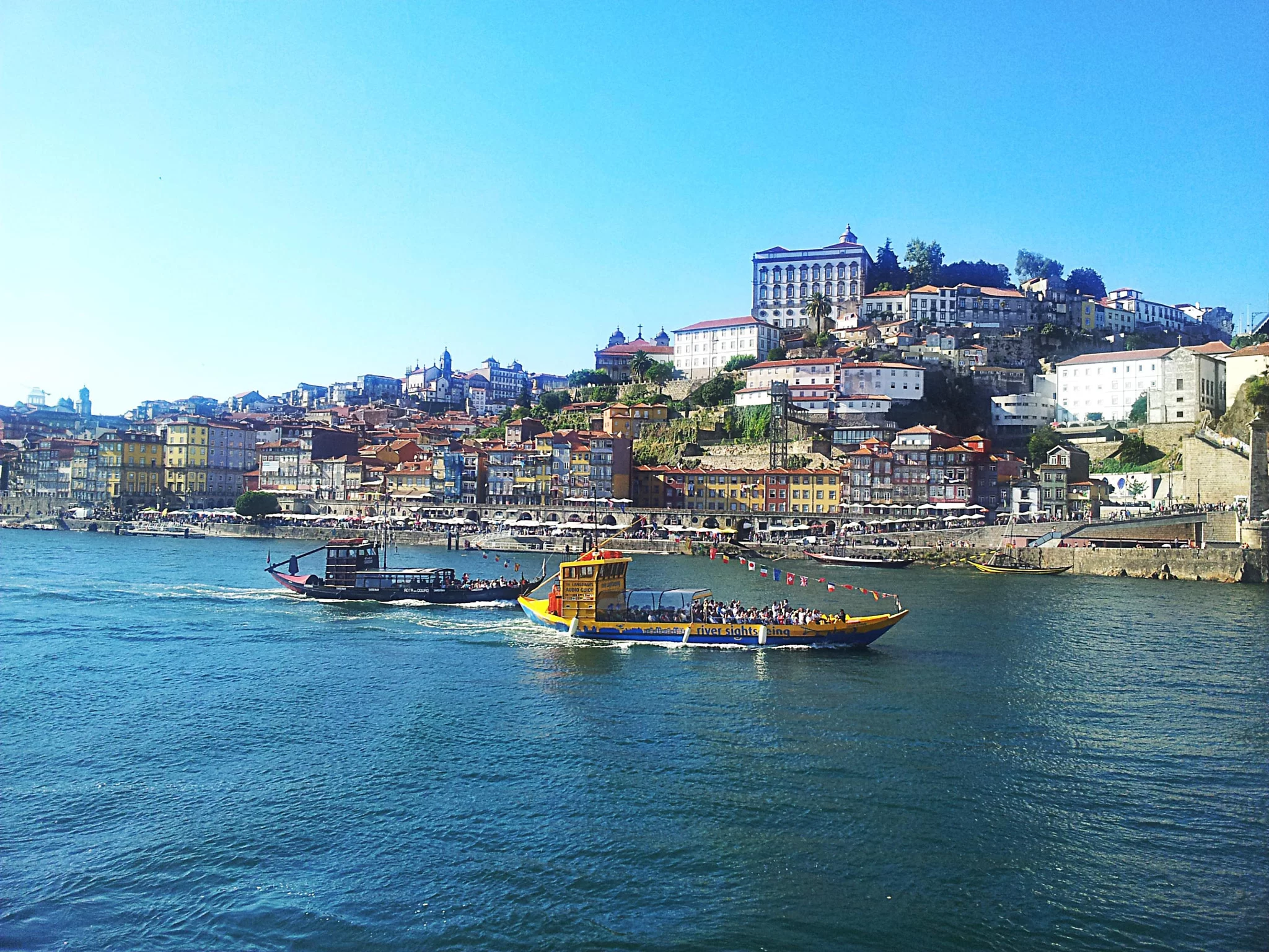 Des bateaux rabelos sur le Douro devant la colline de Porto